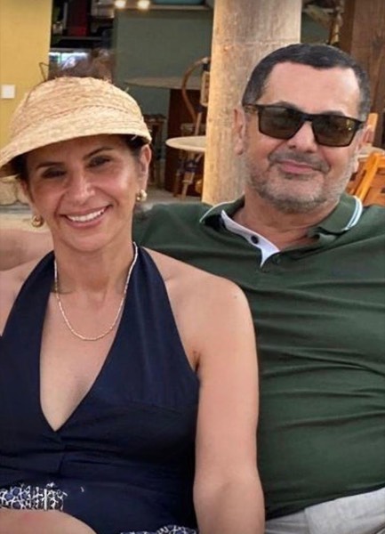 Chad and Nadine side by side at a beach bar, straw visor and sunglasses on
